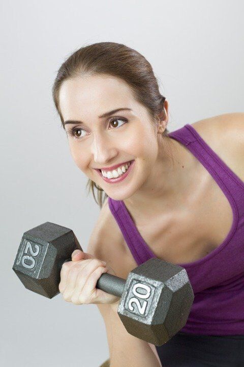 The girl performs exercises to lose weight with a dumbbell